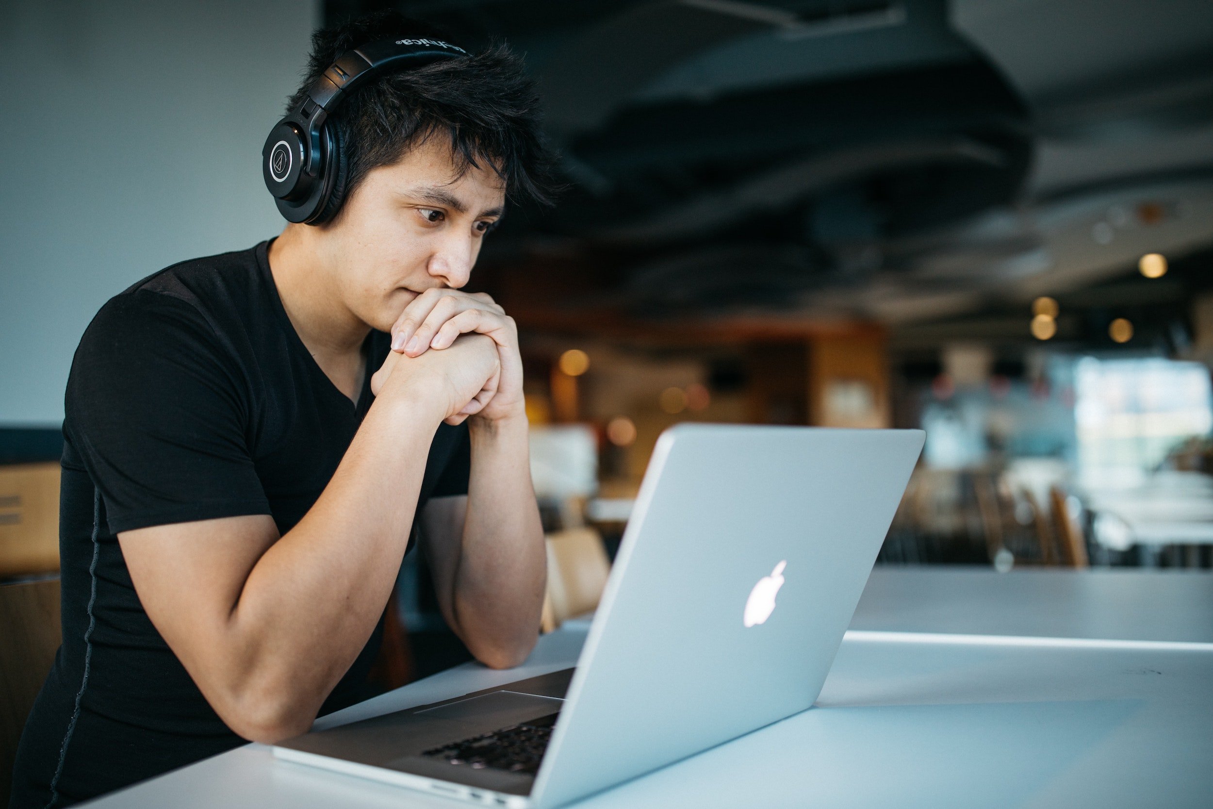 Young male looking at a laptop screen while wearing headphones